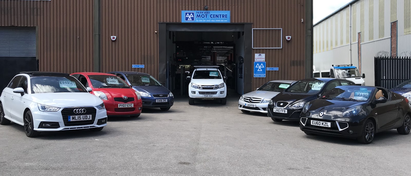 The Parkway MOT Centre forecourt on Bacon Lane, the open workshop bay with used cars for sale lined up outside